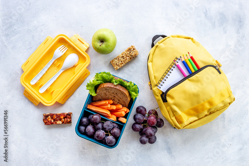 School lunchbox with fruits and yellow backpack  top view