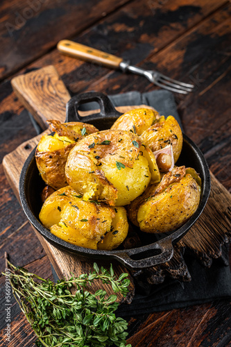 Crushed, Broken potatoes baked in oil with herbs. Wooden background. Top view