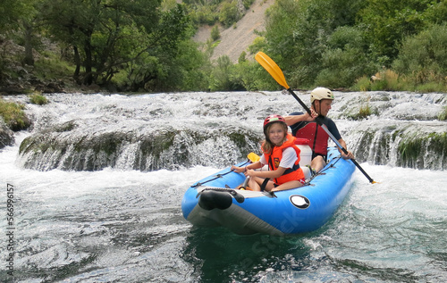 Father and daughter go river rafting in Croatia. Family travel traditions. Paddling in the river