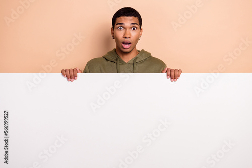 Photo of worried astonished man wear khaki trendy clothes hold empty space board billboard low prices isolated on beige color background