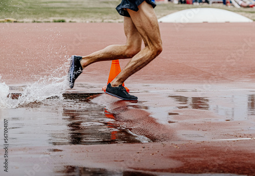 male runner athlete running steeplechase in athletics photo