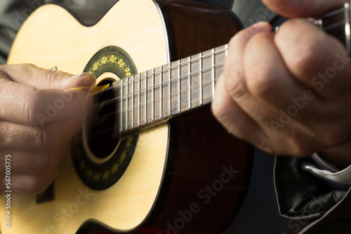 Hands of an white man playing an small samba guitar called cavaquinho or cavaco