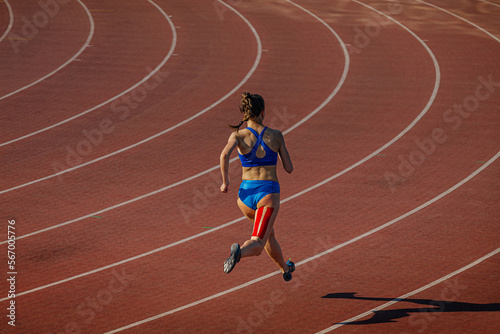Valokuva female athlete running track with kinesio tape on her leg