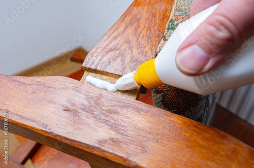 Applying white glue on broken wooden chair at home. Do-it-yourself home furniture repair, giving old things new life concept image. 