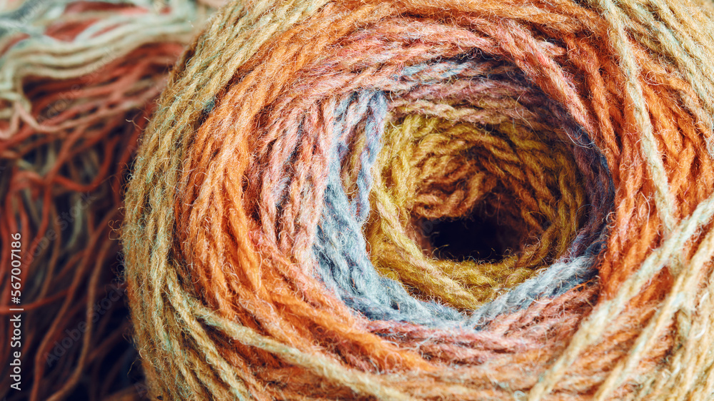 Ball of yarn from pure organic sheep's wool on an unwound skein of woolen threads. Rainbow color. Ball of yarn from pure organic sheep's wool on an unwound skein of woolen threads. Rainbow color.