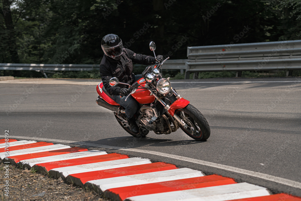 Obraz premium Rider in black helmet on red classic vintage motorcycle in mountains