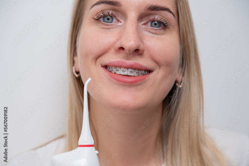 Portrait of a caucasian woman with braces on her teeth holding an irrigator. Portrait of a caucasian woman with braces on her teeth holding an irrigator.