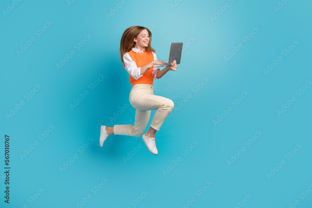 Full length photo of charming cute lady fly air use netbook promoting modern device empty space isolated on blue color background Full length photo of charming cute lady fly air use netbook promoting modern device empty space isolated on blue color background