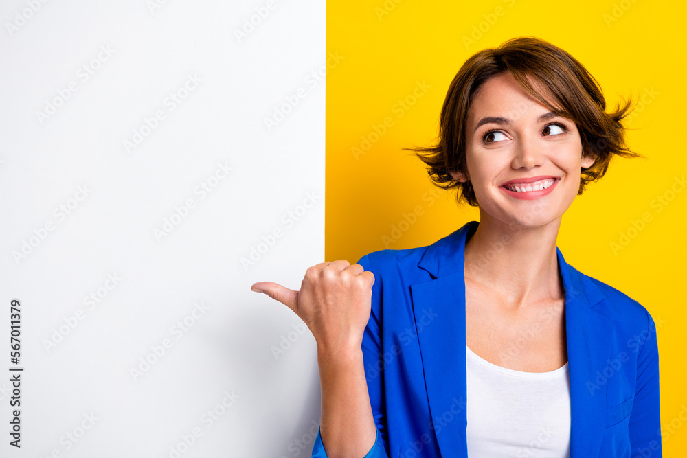 Photo of dreamy sweet woman wear blue jacket looking pointing thumb white wall poster empty space isolated yellow color background Photo of dreamy sweet woman wear blue jacket looking pointing thumb white wall poster empty space isolated yellow color background