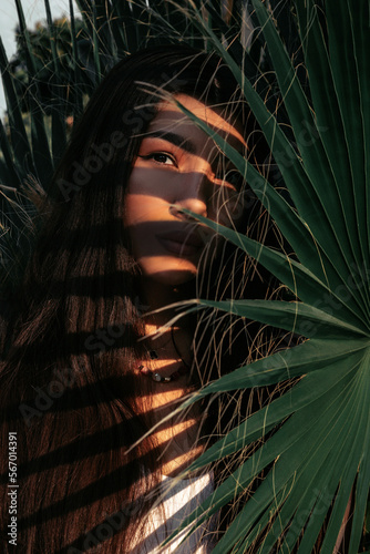 Close-up portrait of a girl among palm leaves.