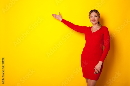 a woman in a red dress indicates the direction of her hand on a yellow background