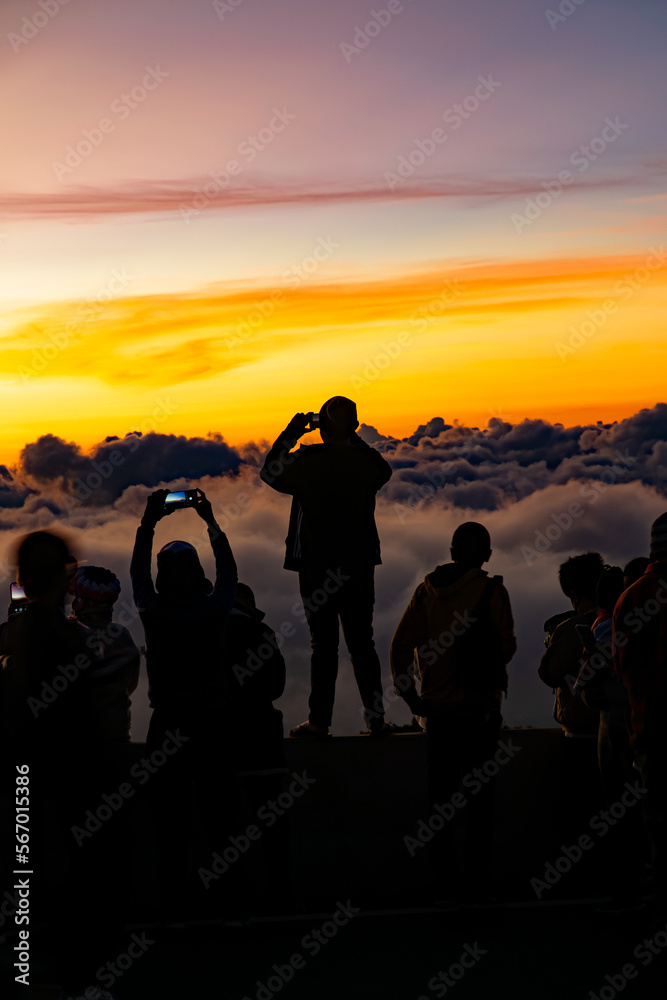 Fototapeta premium Silhouette person group watching floating sea of clouds,Sea of fog, Sky above clouds,taking cloudscape photos with mobile phones in the morning,sun rising,travel long weekend,Inthanon mountain.