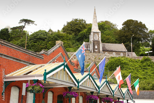 Red brick Cruise Terminal and Heritage Center decorated with flags of the world and Cobh museum which is inside Scots Church, Cobh, near Cork, Ireland.