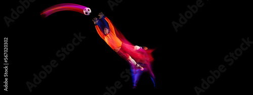 Sportive energetic man, soccer football goalkeeper in action, motion over dark background with mixed neon light. Concept of sport, achievement, competition, goals.