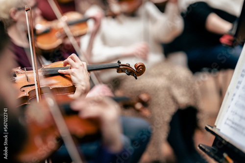 A person playing the violin or viola during a classical symphony orchestra rehearsal