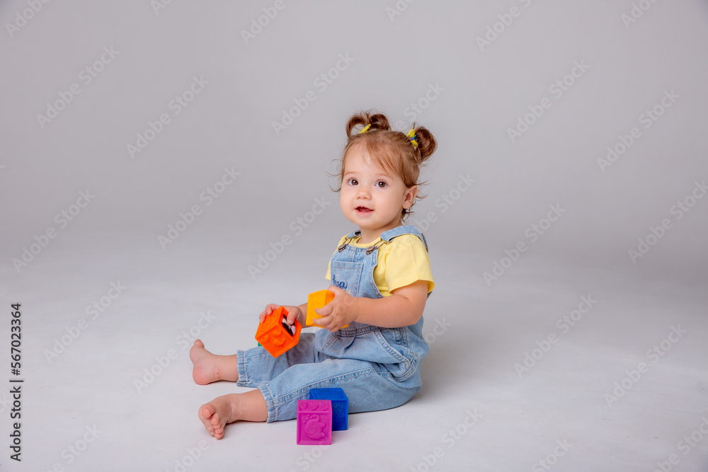 little baby girl is sitting on a white background and playing with colorful cubes. kid's play toy cubes
little baby girl is sitting on a white background and playing with colorful cubes. kid's play toy cubes