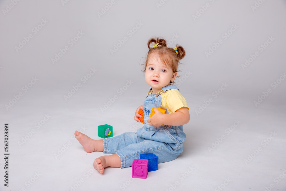 little baby girl is sitting on a white background and playing with colorful cubes. kid's play toy cubes
little baby girl is sitting on a white background and playing with colorful cubes. kid's play toy cubes