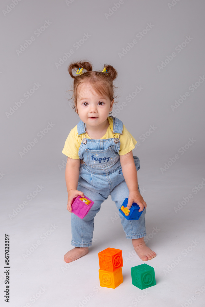 little baby girl is sitting on a white background and playing with colorful cubes. kid's play toy cubes
little baby girl is sitting on a white background and playing with colorful cubes. kid's play toy cubes
