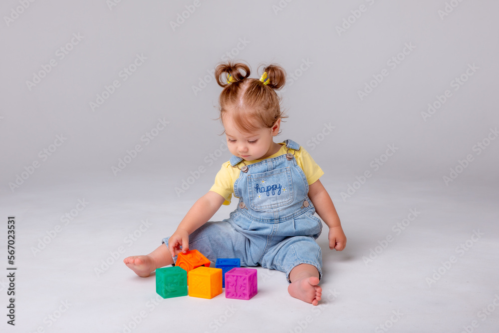 little baby girl is sitting on a white background and playing with colorful cubes. kid's play toy cubes
little baby girl is sitting on a white background and playing with colorful cubes. kid's play toy cubes