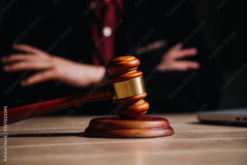 Justice and law concept.Male judge in a courtroom with the gavel, working with, computer and docking keyboard, eyeglasses, on table in morning light Justice and law concept.Male judge in a courtroom with the gavel, working with, computer and docking keyboard, eyeglasses, on table in morning light