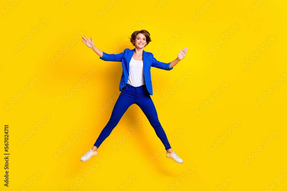 Full length photo of shiny adorable woman wear blue jumping high like star isolated yellow color background Full length photo of shiny adorable woman wear blue jumping high like star isolated yellow color background