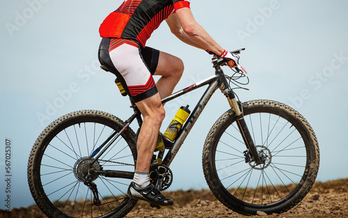 Fototapeta Naklejka Na Ścianę i Meble -  close-up male athlete mountain biker in background sky