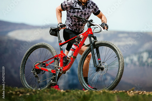 athlete cyclist walking mountain bike on mountain trail
