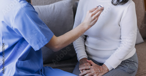 Homecare nursing service and elderly people cardiology healthcare. Close up of young hispanic female doctor nurse check mature caucasian man patient heartbeat using stethoscope during visit