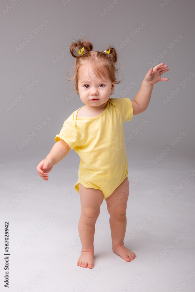 baby girl starting to walk takes her first steps on a white background