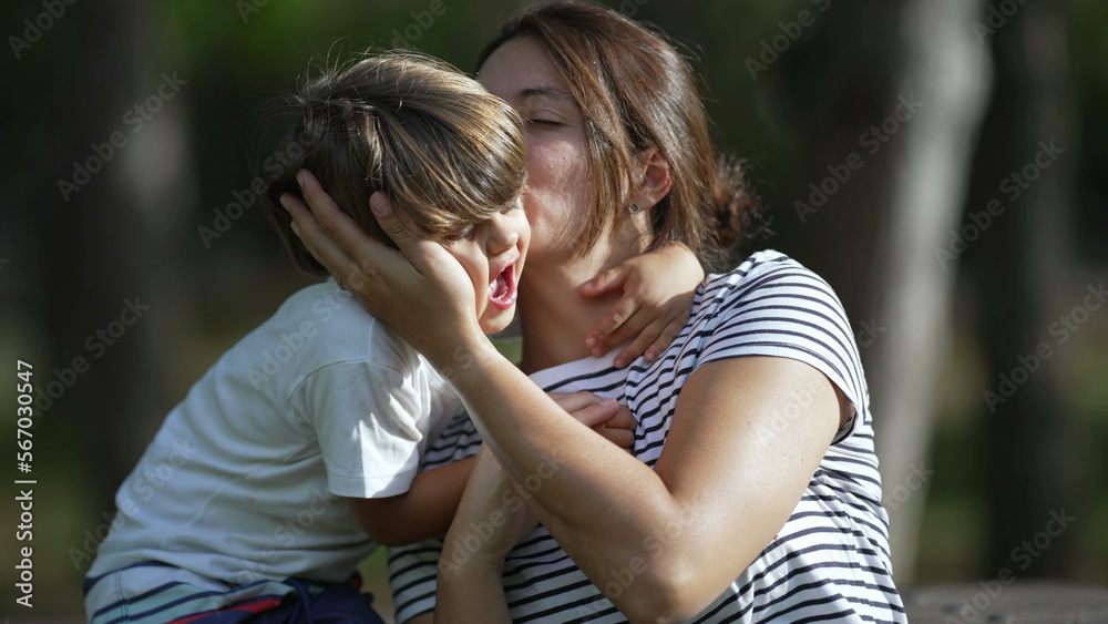 Mother and child love and affection. Little boy son embracing mom outside at park. Kid kissing mom on cheek. Motherhood care Mother and child love and affection. Little boy son embracing mom outside at park. Kid kissing mom on cheek. Motherhood care