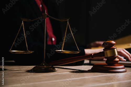 Justice and law concept.Male judge in a courtroom with the gavel, working with, computer and docking keyboard, eyeglasses, on table in morning light