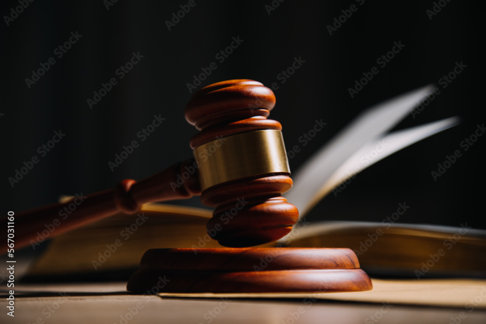 Justice and law concept.Male judge in a courtroom with the gavel, working with, computer and docking keyboard, eyeglasses, on table in morning light Justice and law concept.Male judge in a courtroom with the gavel, working with, computer and docking keyboard, eyeglasses, on table in morning light