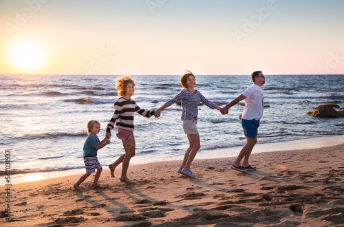 Happy family of father, mother, little son and adult daughter, having fun holding hands, playing on beach during summer holidays. concept of happy family relationships, togetherness, joy and vacation