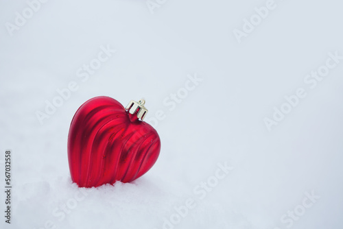 Valentines day background with red love heart on white snow.