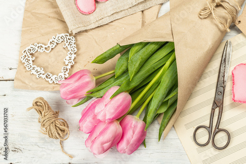 Fototapeta Naklejka Na Ścianę i Meble -  Bouquet of fresh pink tulips. Making spring floral decorations. Tools, vintage scissors, craft paper