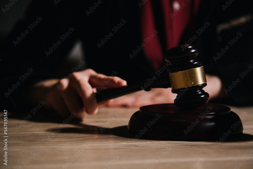 Justice and law concept.Male judge in a courtroom with the gavel, working with, computer and docking keyboard, eyeglasses, on table in morning light Justice and law concept.Male judge in a courtroom with the gavel, working with, computer and docking keyboard, eyeglasses, on table in morning light