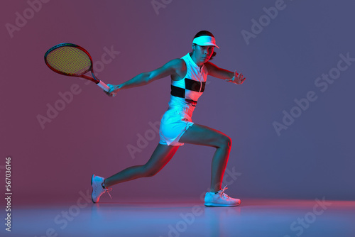 Portrait of young professional female tennis player in sports uniform in motion, action over gradient pink-purple background in neon light. Sport, fashion, energy, motivation concept © Lustre Art Group 