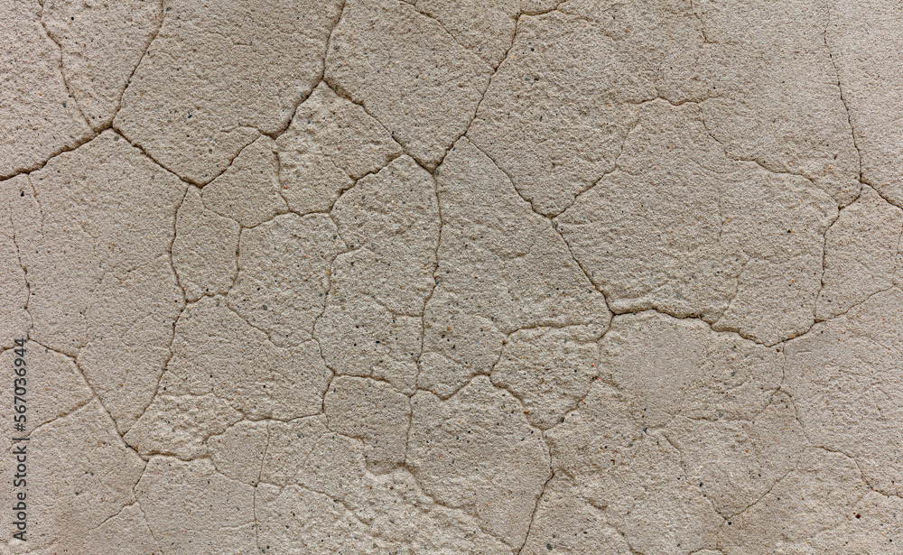 Fototapeta premium Destroy dry sandstone with time in the form of a network of uneven cracks of different depths of beige color. background texture