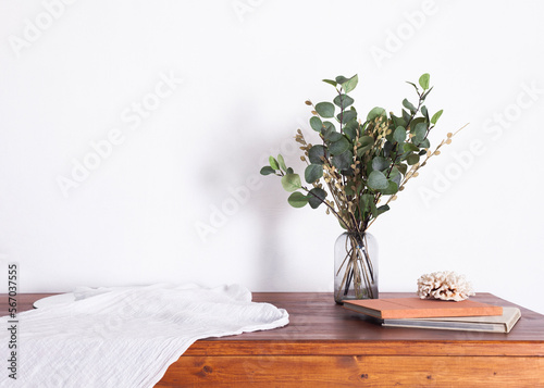 a bouquet of plants in a vase stands on a table in a minimalistic interior with a white tablecloth