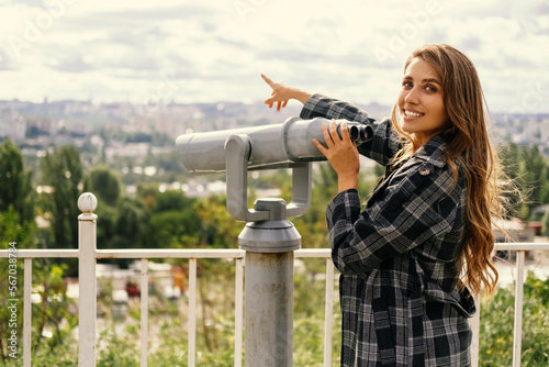 Cheerful woman points to the city she was looking at in sightseeing binoculars.