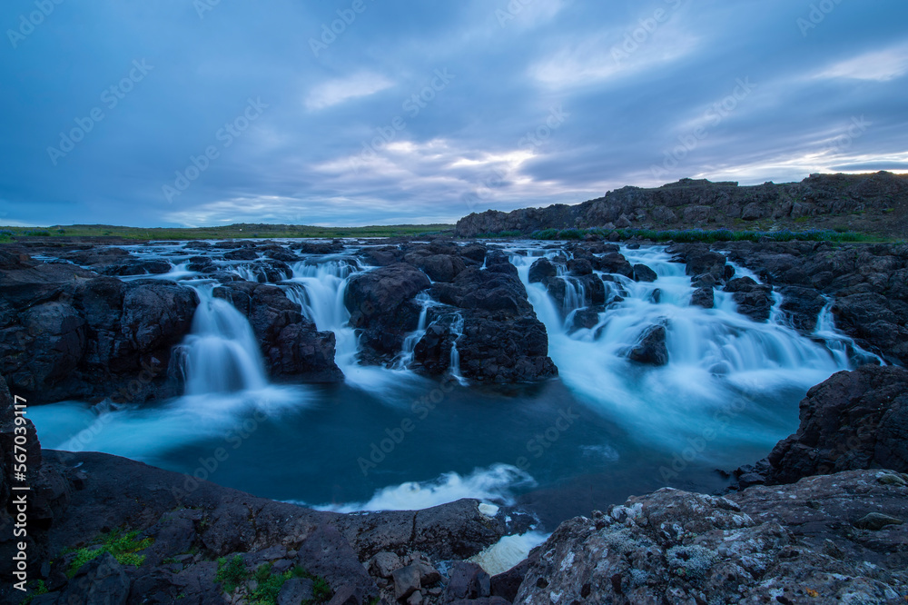 Obraz premium Majestic summer sunrise on Bruarfoss Waterfall. The 'Iceland’s Bluest Waterfall.' Blue water flows over stones. Midnight sun of Iceland. Visit Iceland. Beauty world.