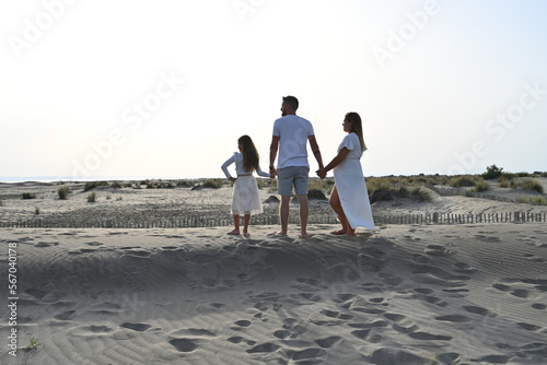 family and pregnant woman at the beach with a white dress