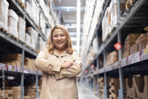 Portrait Plus size female worker looking at camera while working in large warehouse