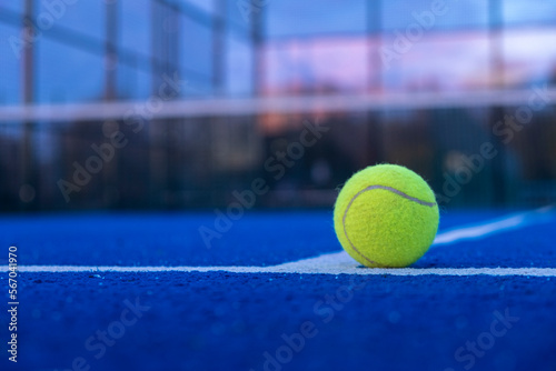 ball on the line of a blue paddle tennis court at sunset, racket sports concept