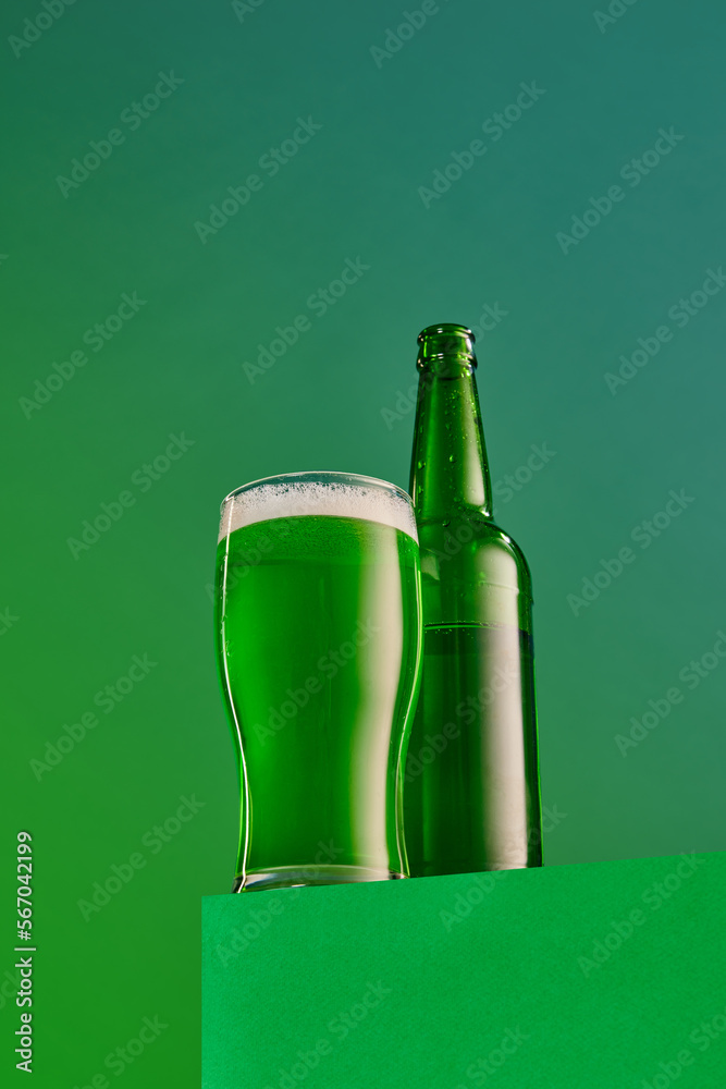 Popular and favorite drink. Glass and bottle of green foamy beer over green background. Concept of st patrick's day celebration, brewery, traditions, alcohol drinks, taste, Irish holiday Popular and favorite drink. Glass and bottle of green foamy beer over green background. Concept of st patrick's day celebration, brewery, traditions, alcohol drinks, taste, Irish holiday