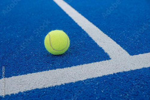ball next to the line of a blue tennis paddle tennis court at sunset © Vic