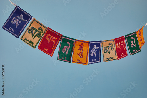 Tibetan Buddhist flags against blue background. Text on flags Om mani padme hum meaning The jewel is in the lotus.