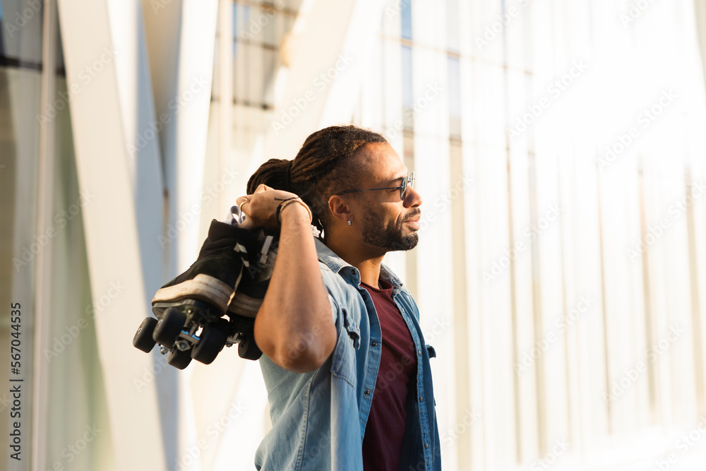 Black man enjoy outside. Modern man posing with roller skates.. Black man enjoy outside. Modern man posing with roller skates..