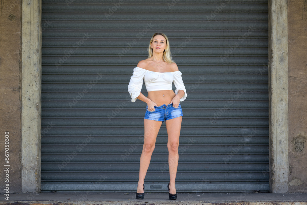 Obraz premium Attractive woman posing in front of a roller shutter