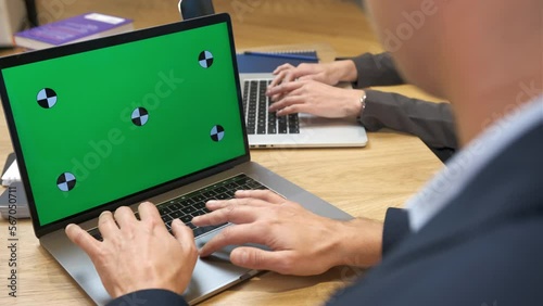 Colleagues in the office working on laptops. A man and a woman are typing on a keyboard. The man reads the typed text. The concept of business, career development and success. Green screen. Close-up.